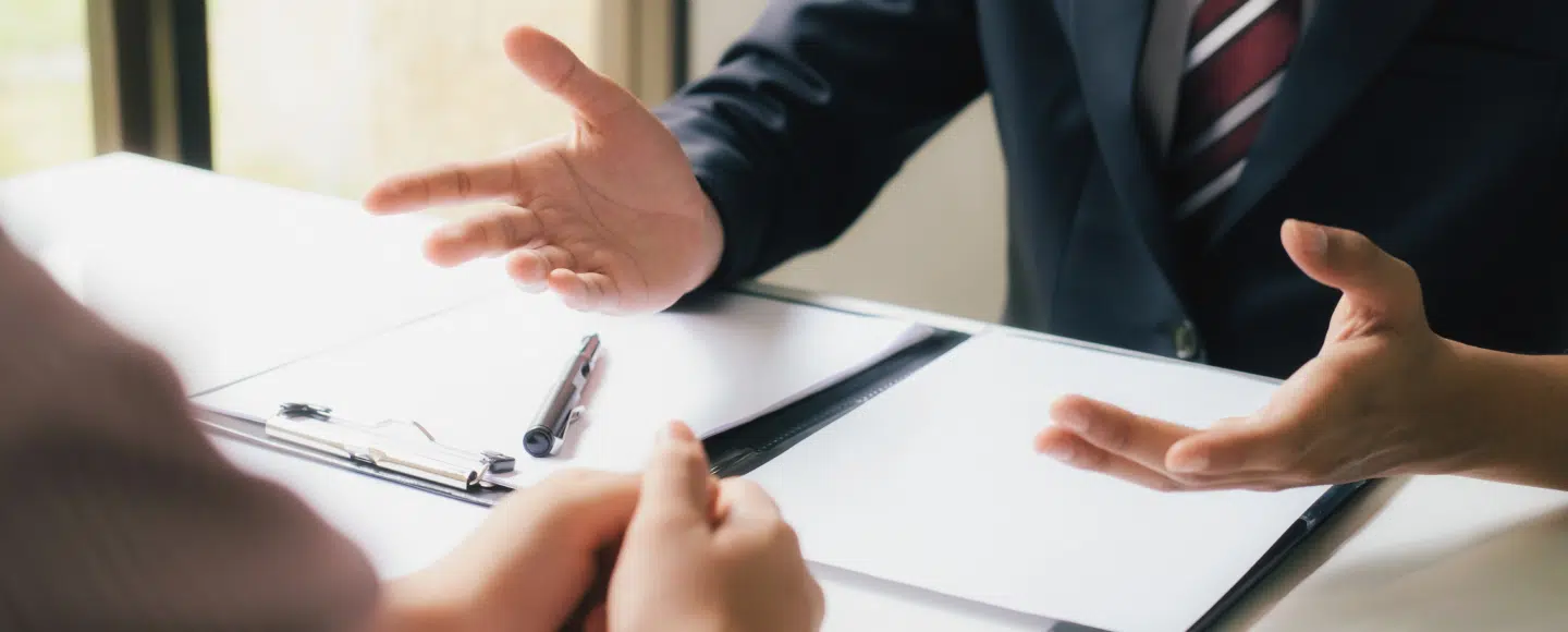 Attorney discussing legal documents with a client at a desk during a consultation.